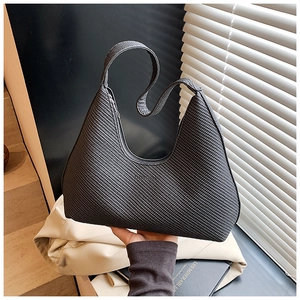 Détail du sac hobo noir tressé montrant la texture en tricot et la bandoulière minimaliste