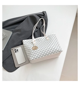 Detailed shot of beige quilted tote bag with black M patterns and golden metal pendant