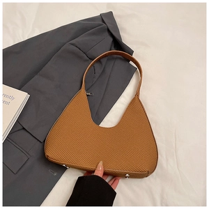 Détail de la texture tressée et des pieds en métal d'un sac à main hobo marron