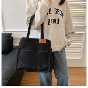 Détail du sac fourre-tout en toile noire avec poche à surpiqûres et garniture en cuir