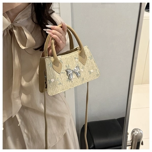 Close-up of woven straw bag with floral embroidery and silver metal bow detail