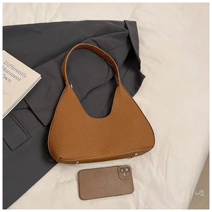 Détail d'un sac demi-lune marron tissé avec pieds en métal et fermeture éclair