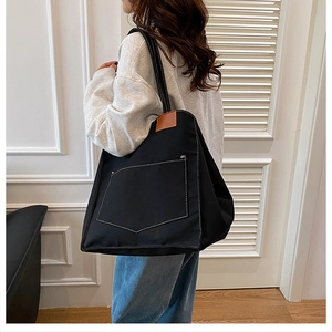 Vue latérale du grand sac cabas en toile noire avec surpiqûres sur un mannequin