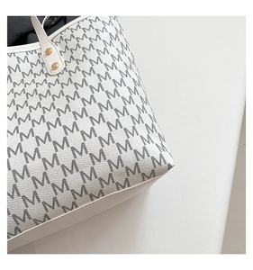 Macro shot of large tote bag showing white leather texture and gold metal rivets