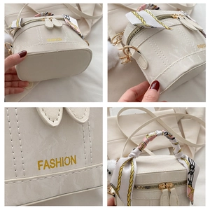 Macro details of cream bucket bag showing silk scarf handle and gold fashion lettering