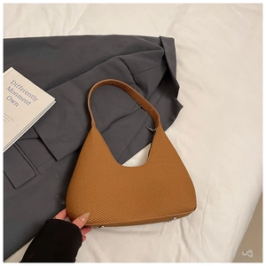 Détail du sac hobo caramel avec texture fine et pieds métalliques sur une veste de costume