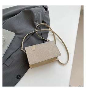 Detail of beige textured mini crossbody bag with glitter finish and metallic strap