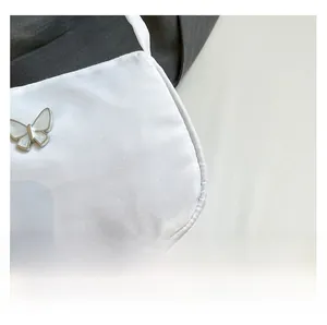 Close-up of white fabric texture and silver butterfly ornament on the shoulder bag
