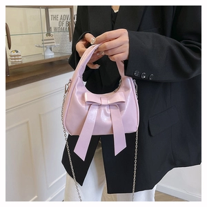 Detail of pink bow handbag with glossy PU leather finish and delicate metal chain strap