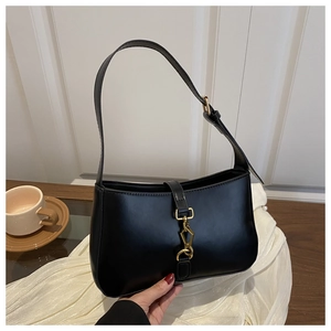 Détail d'un sac sous les bras en similicuir noir vintage avec un fermoir à piston en bronze