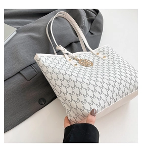Detailed view of white tote bag with M-letter monogram print and golden metal charm