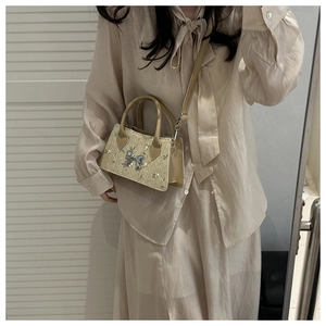 Straw bag with silver bow buckle and floral embroidery shown as a crossbody wear