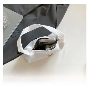 Interior capacity of the white nylon shoulder bag showing space for phone and makeup
