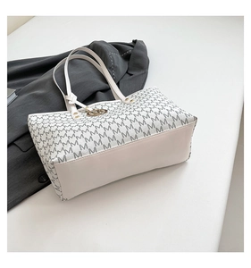 Detail of the monogram letter pattern and golden logo on the cream tote bag
