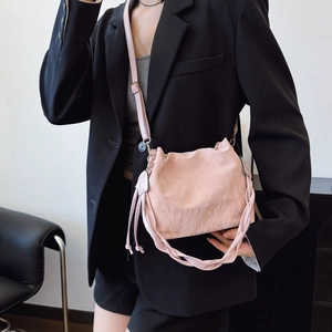 Pink bucket bag with textured pleats, woven handle and adjustable crossbody strap