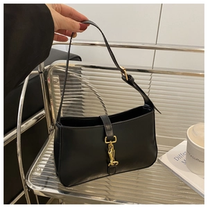 Detail of a black minimalist underarm bag with a vintage gold buckle and smooth texture