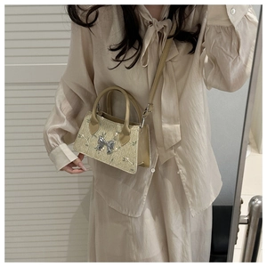 Detail of a beige woven straw crossbody bag with floral embroidery and bow detail