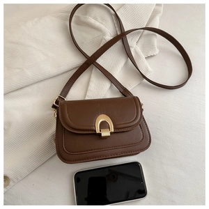 Details einer braunen Satteltasche mit Hufeisenschnalle und Handy zum Größenvergleich