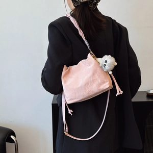 Pink pleated bucket bag with plush charm, cross-body style shown on model