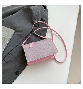 Close-up of pink glitter texture on small square crossbody bag with leather strap