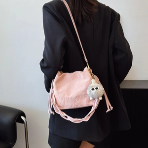 Pink crossbody bucket bag with pleated texture, woven strap and fuzzy monster charm