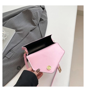 Detail view of pink flap crossbody bag with golden magnetic snap and black interior