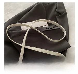 Gros plan du sac bandoulière blanc en cuir grainé avec sangle réglable et boucle dorée