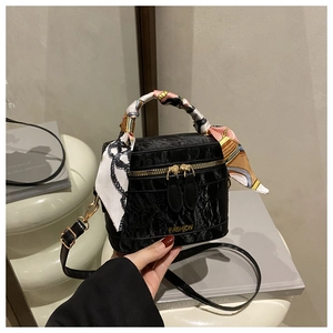 Detail of black velvet handbag with pleated texture, gold FASHION logo, and silk scarf handle
