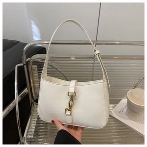 Detail of white vintage underarm bag featuring a signature golden piston lock closure