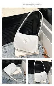 Detail view of white nylon underarm bag with silver butterfly charm and zipper