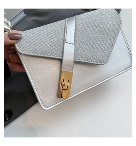 Close-up of metallic silver crossbody bag with gold buckle and textured leather flap