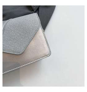 Detailed view of silver crossbody bag featuring woven texture and metallic leather finish