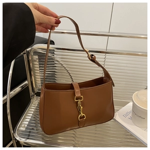 Detail of vintage brown leather handbag with gold clasp on minimalist metal shelf