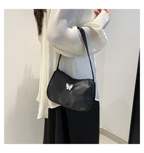 Detail of black nylon underarm bag featuring a 3D white butterfly and zipper closure