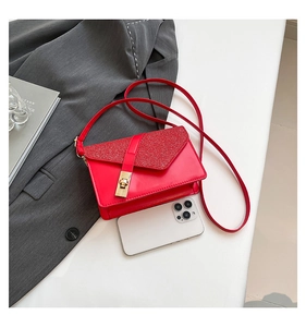Detailed view of mini red glitter crossbody bag with gold lock next to a smartphone
