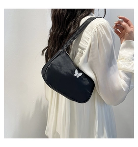 Detail of black crescent shoulder bag with white butterfly charm on nylon fabric