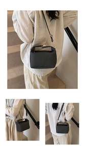 Close-up of textured black trapezoid bag with gold hardware and adjustable strap