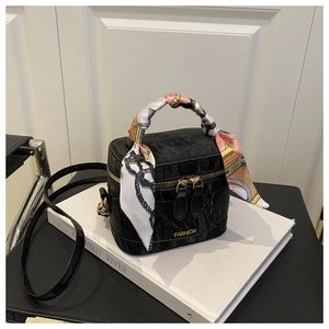 Detail of black textured velvet vanity bag with silk scarf handle and gold hardware