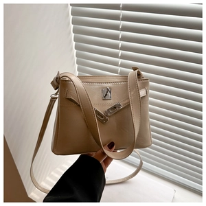 Detail of beige trapezoid crossbody bag with silver twist lock and pebble texture
