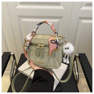 Detail of light green bucket bag featuring printed silk scarf handle and plush doll charm