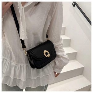 Classic black PU leather crossbody bag with gold horseshoe buckle worn by a model
