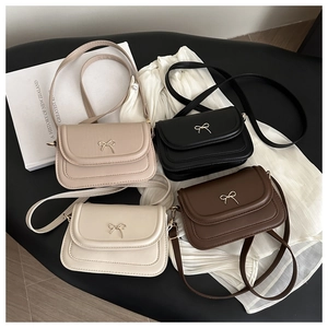 Detail view of stylish square crossbody bags in four colors with gold bow buckles