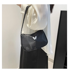 Detail of black hobo bag featuring a white 3D butterfly ornament and smooth shoulder strap