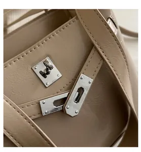 Close-up of beige handbag featuring a classic rectangular metal swivel lock and texture