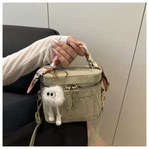 Detail of light green marble-textured handbag with scarf handle and plush monster charm
