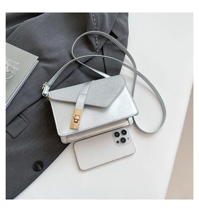 Detail of silver metallic textured crossbody bag with gold buckle and weave pattern