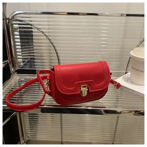 Detail of red lychee textured leather handbag with a polished gold metallic buckle