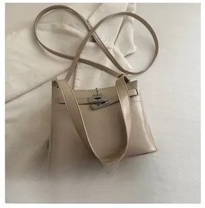 Close-up of beige leather crossbody bag with metal buckle and mobile phone for scale
