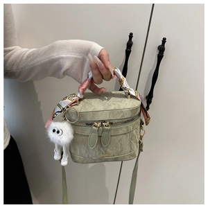 Detail of light green ruched bag with silk scarf handle and plush ball charm