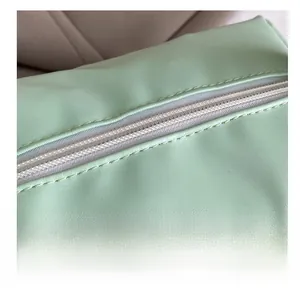 Close-up of precise white stitching and smooth PU leather texture on a mint green handbag